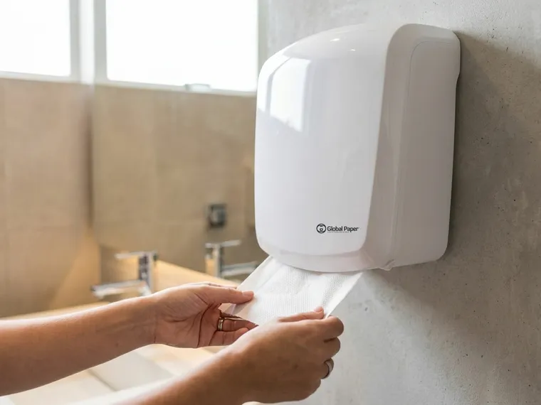 Mãos secando com papel toalha interfolhado retirado de um dispenser